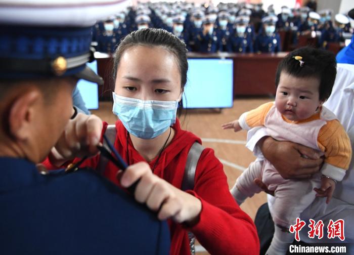 新消防員楊振的妻子彭莉與女兒現(xiàn)場見證丈夫加入“火焰藍”的神圣時刻?！⒅铱?攝